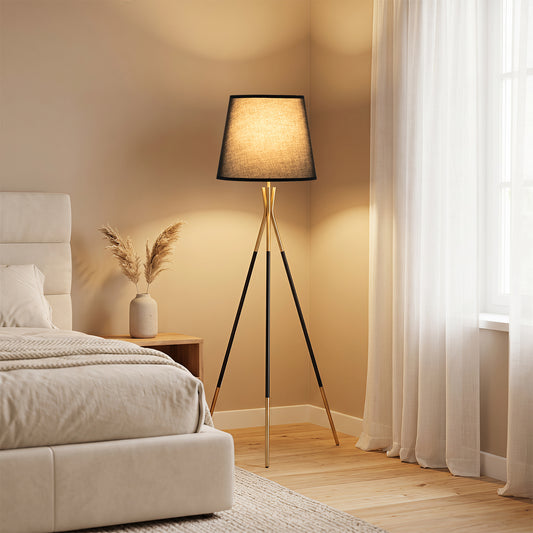 The standing lamp placed in a bedroom next to a bed with warm lighting