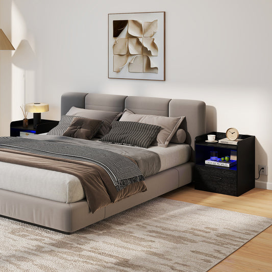 The black bedside table placed next to a grey upholstered bed in a modern bedroom setting