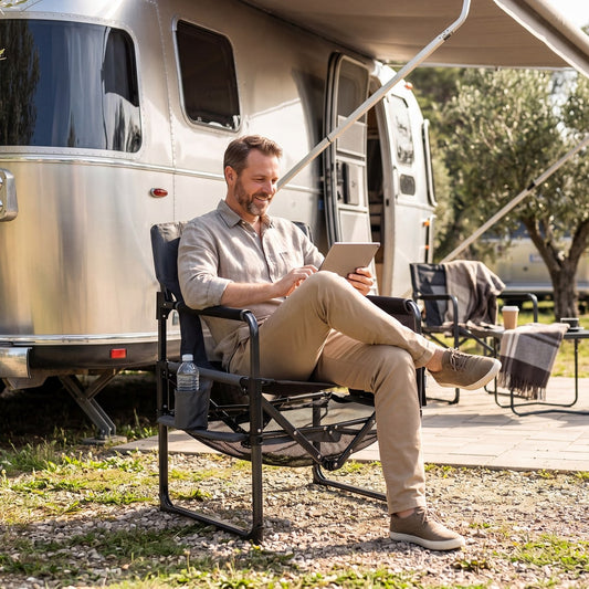 The camping furniture being used by a man sitting outside a caravan with a tablet