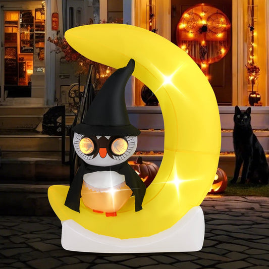 The Halloween owl inflatable decoration is lit up at night in a garden setting with a black cat nearby