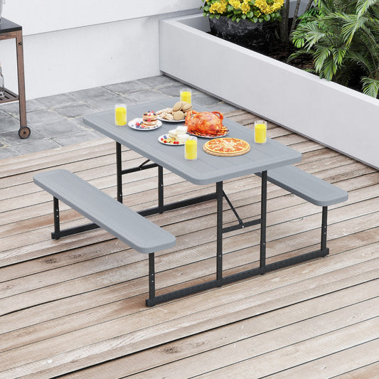 The grey picnic table and benches set up on a patio with food on the table