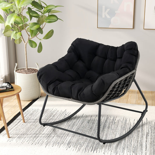 The patio rocking chair is shown indoors on a rug next to a plant and side table