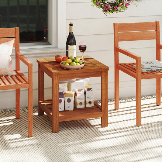 The wooden table placed between two chairs on a patio with food and wine