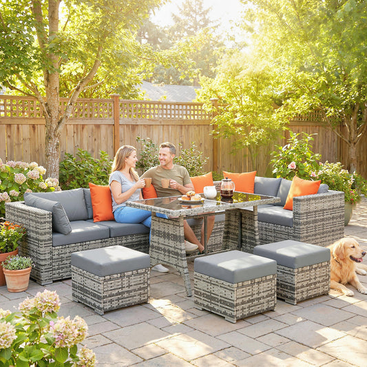 A couple relaxing on the grey woven garden furniture set with orange cushions in a sunny garden