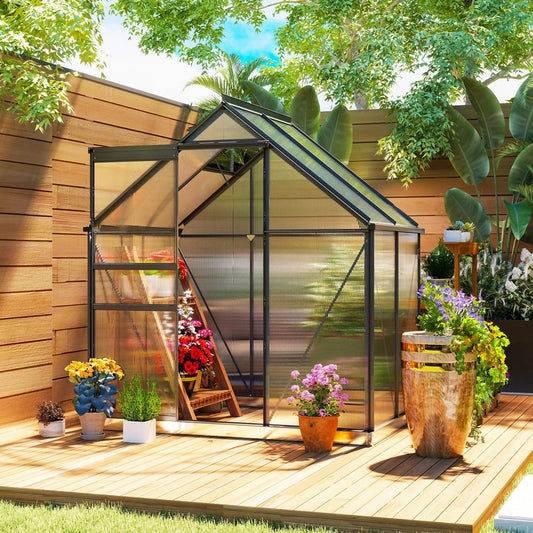 The greenhouse placed on a wooden deck in a garden filled with potted flowers and plants
