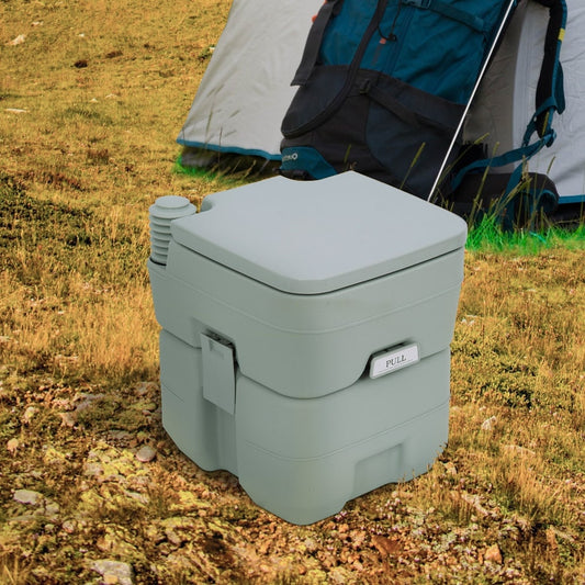 The portable camping toilet placed on grass in front of a tent and a hiking backpack