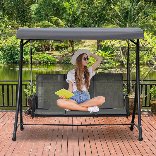 A woman sits on the three-seater garden swing chair on a wooden deck by a lake