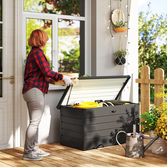 The garden storage box placed on a wooden patio with a person putting items inside