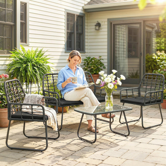 Woman relaxing on a rattan garden loveseat with a coffee table and armchairs nearby