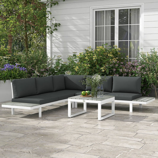 The garden furniture set arranged on a stone patio in front of a house with flowering plants