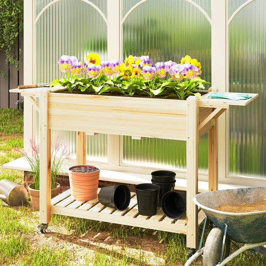 The wooden raised planter filled with colourful pansies and surrounded by pots and gardening tools