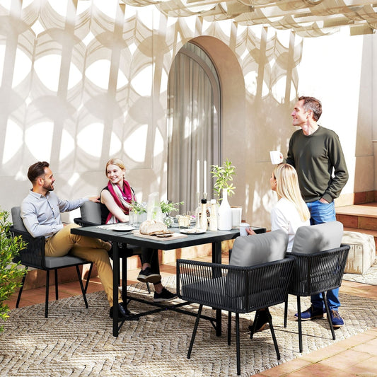 The rattan furniture set arranged on a patio with four people sitting and eating around the table