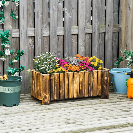 The wooden planter placed on a wooden deck in front of a garden fence with other pots
