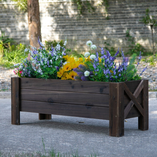 The wooden planter box filled with colourful flowers placed on a patio outdoors