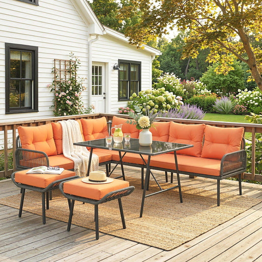 The rattan furniture set arranged on a wooden deck with a white house in the background