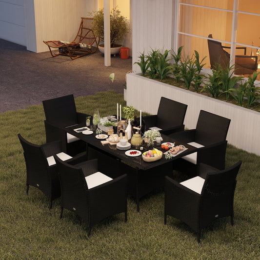 Black rattan garden furniture set with six armchairs arranged around a glass top table, set for a meal outdoors