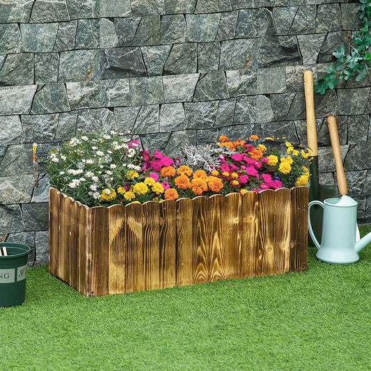 A wooden planter box filled with colourful flowers, set against a stone wall