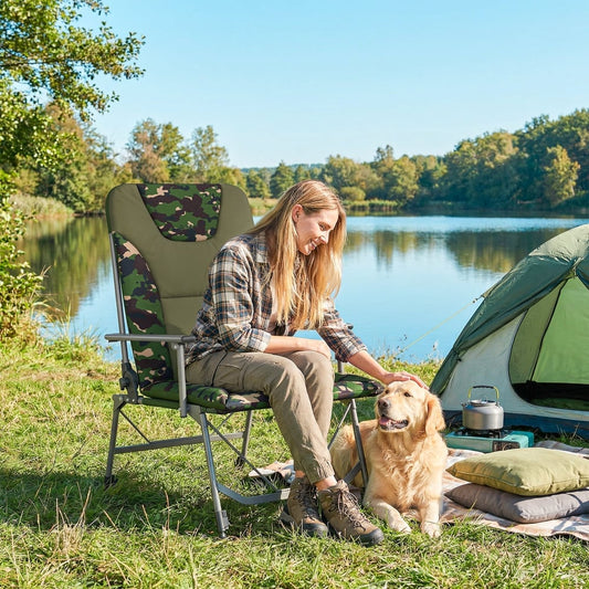 Woman and dog relaxing by a lake next to a tent with the camping chair set up