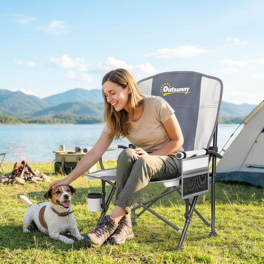 Woman sitting in the padded camping chair outdoors next to a lake with a dog