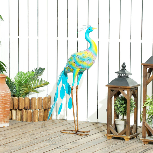 A colourful metal peacock garden ornament standing on a wooden deck next to lanterns