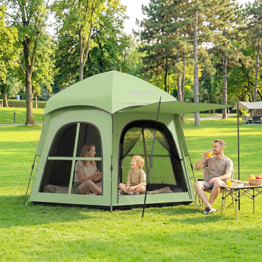 A green camping tent pitched in a grassy field with two people sitting inside and one person outside