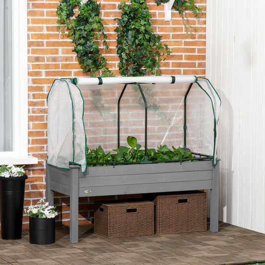 The elevated planter box placed on a patio against a brick wall with green climbing plants