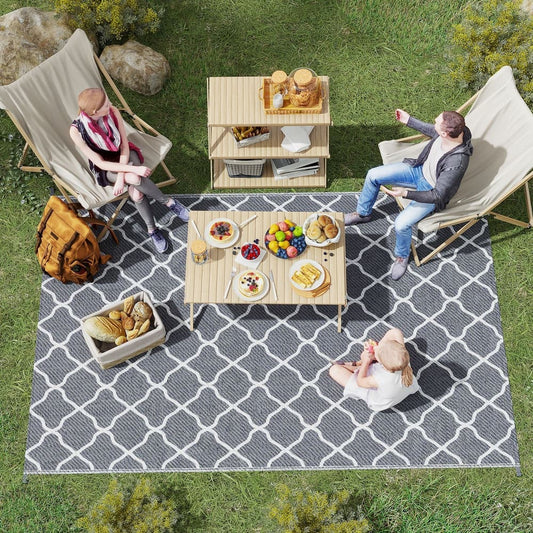 The outdoor rug in use at a picnic with a table and chairs on it