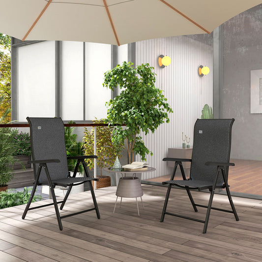 The garden chairs placed on a wooden patio under a parasol with a small table and plants