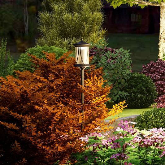 The garden lighting lamp post standing amongst colourful bushes and flowers at dusk