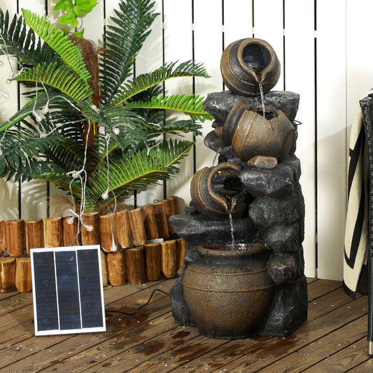 The garden fountain with four tiers of jars and rocks, shown outdoors with a solar panel