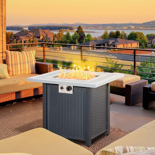 The gas firepit table is set up on a patio with sofas and a view of water