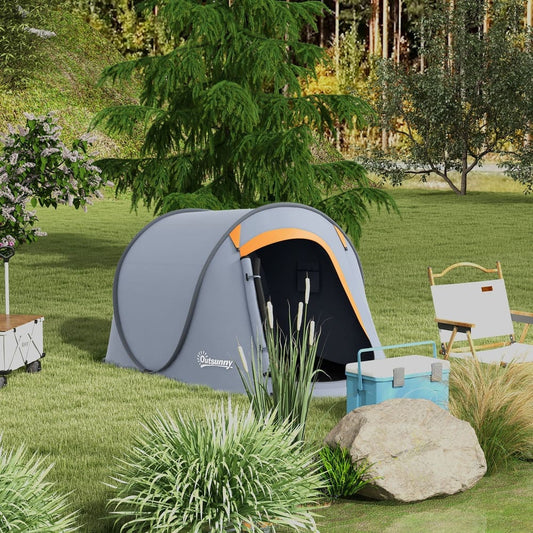 The grey pop-up dome tent set up in a garden with trees and grass, next to a cooler and chair
