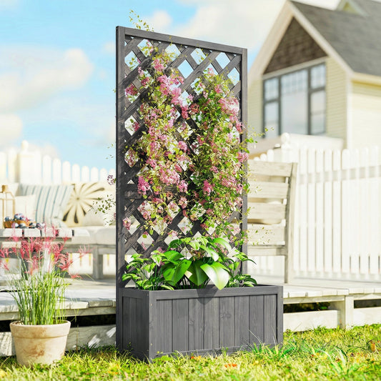 The wooden planter with trellis filled with blooming flowers standing on a sunny garden patio