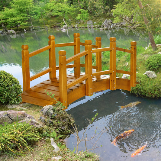 The wooden garden bridge positioned over a small pond with fish in a lush green garden