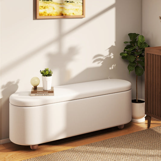 White oval storage bench in a living room with a book and plant on top