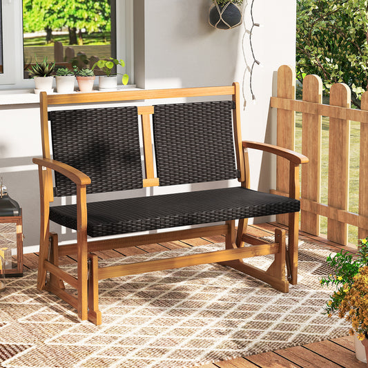 The rattan glider bench swing is placed on a patio rug on a paved patio area