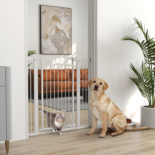 The dog gate installed in a doorway with a cat walking through the small flap and a dog sitting