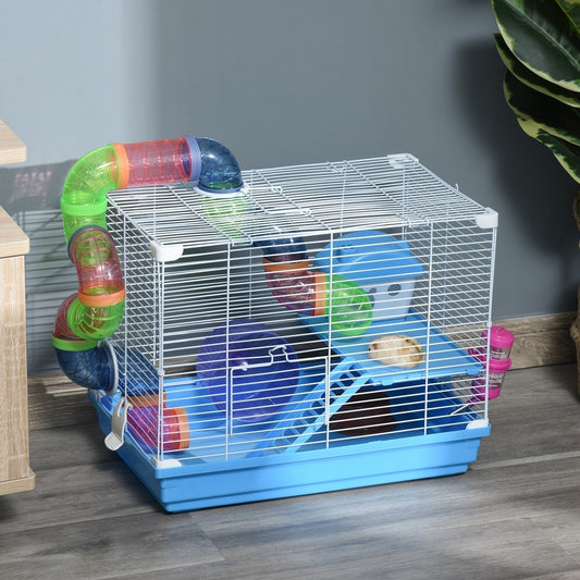 The hamster hutch is set up on a wooden surface next to a plant and a cabinet