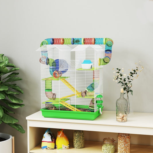 The hamster hutch with tubes and accessories is displayed on a white cabinet next to a plant and vase
