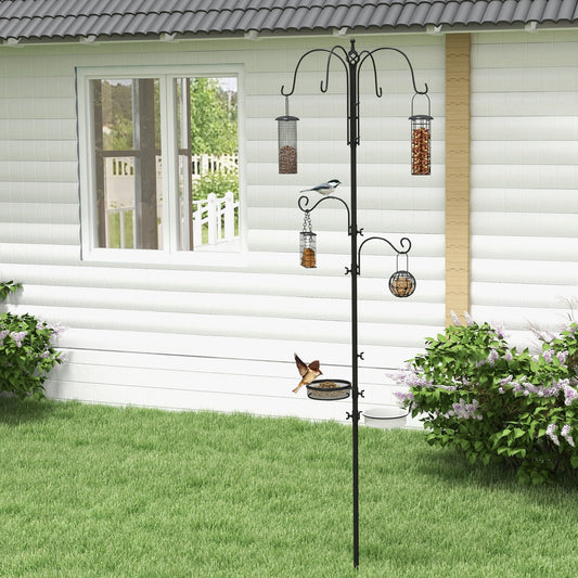 The bird feeding station standing in a garden with small birds visiting the hanging feeders