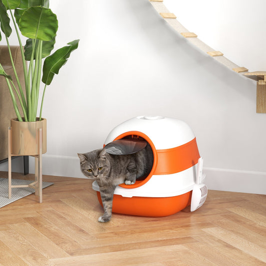 The litter box placed on a wooden floor in a bright living room with a cat exiting