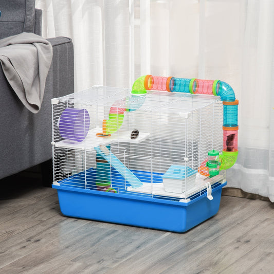 The hamster hutch is set up in a room on a wooden floor next to a grey sofa