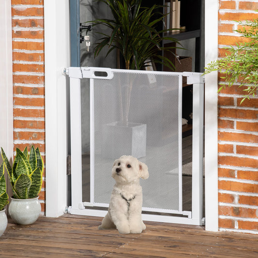 A small white dog sits patiently in front of the white safety gate installed in a doorway