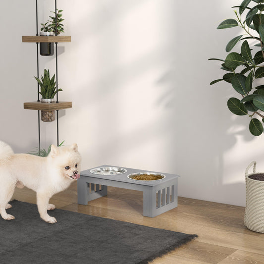 The raised dog feeder placed on a wooden floor next to a small dog in a bright living room