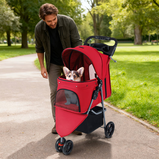 A man pushing the red pet stroller with a corgi puppy inside while walking in a park