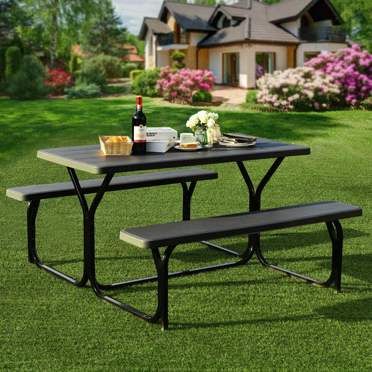 The outdoor picnic table bench set on a green lawn with a house in the background