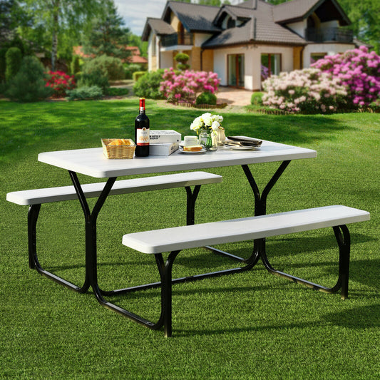 The white picnic table bench set on a green lawn with a house in the background