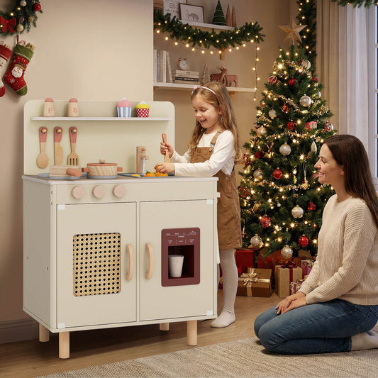 The play kitchen set being used by a young girl in a room decorated for Christmas