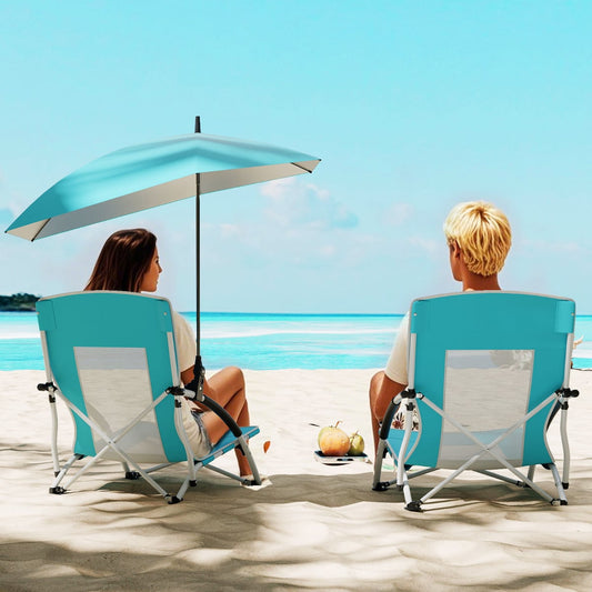 Two people sitting on the blue camping furniture on a sandy beach under a clear blue sky
