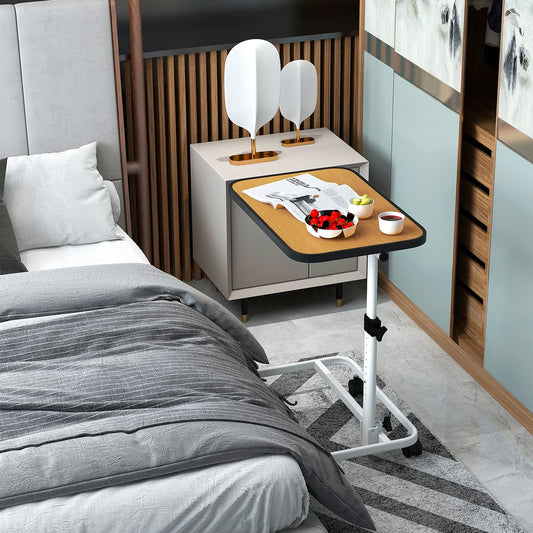 The bedside table next to a bed with a book and a bowl of fruit on top